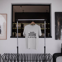 White t-shirt with text hanging on a rack in a modern interior setting