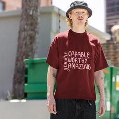 Person wearing a maroon t-shirt with motivational text outdoors