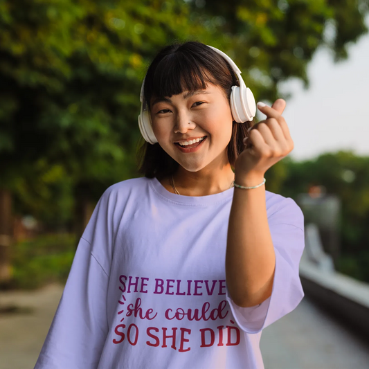 Woman wearing headphones and a t-shirt with an inspirational quote, outdoors.