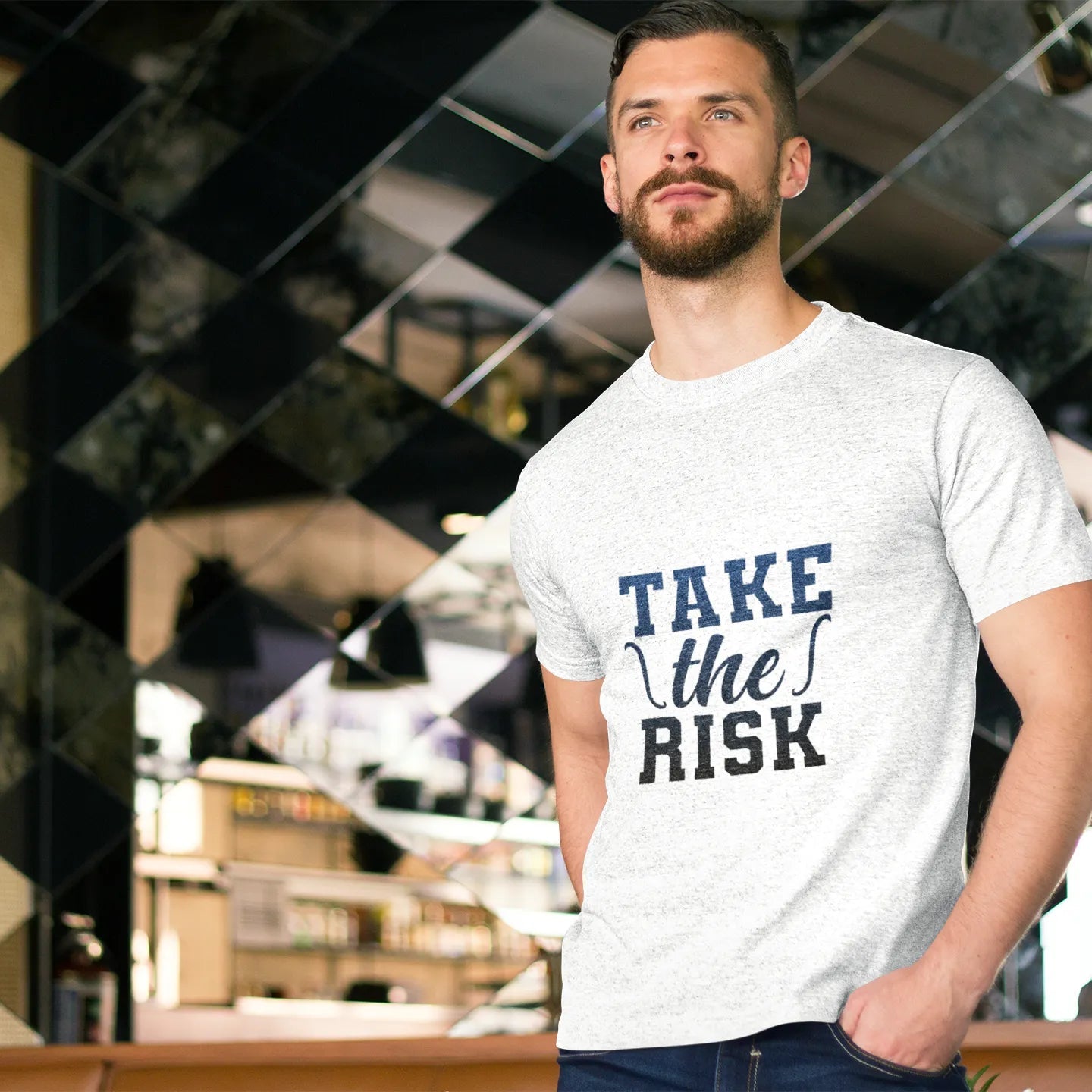 Man wearing a white t-shirt with 'Take the Risk' text in a modern indoor setting
