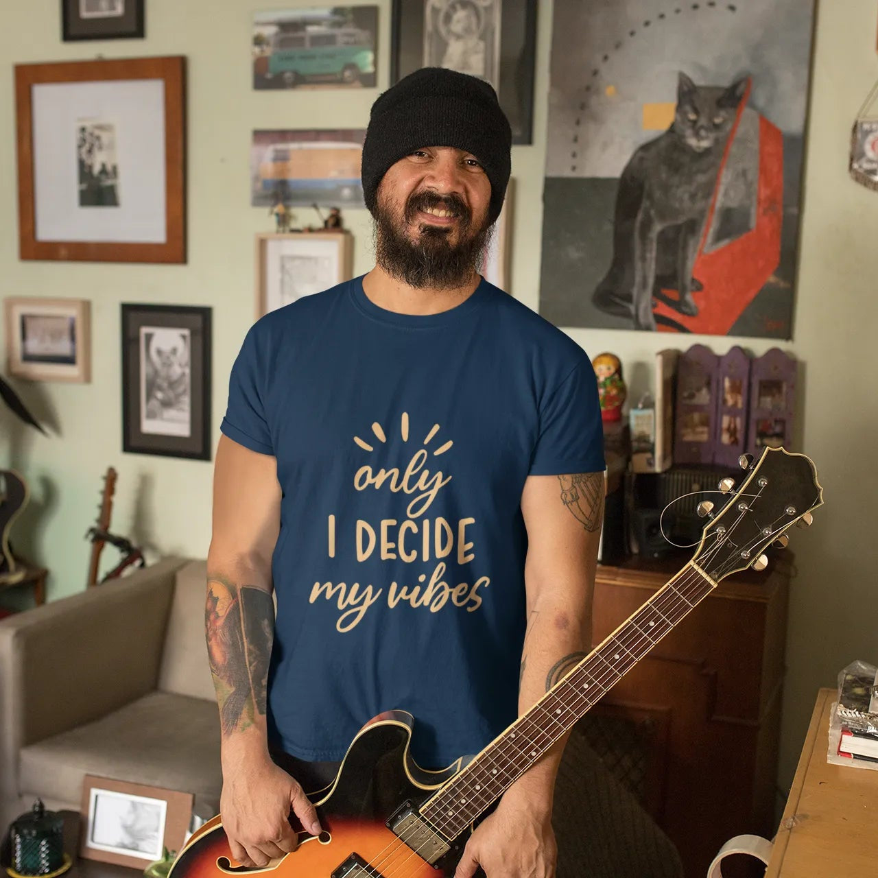 Man holding a guitar in a room with various decorations on the walls.