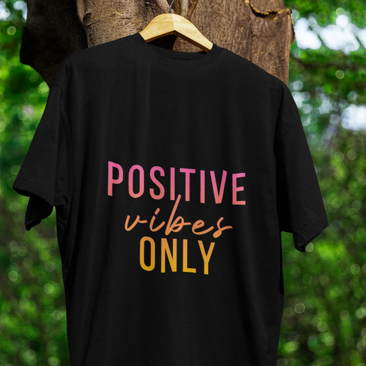 Black t-shirt with 'Positive vibes only' text on a hanger against a natural background