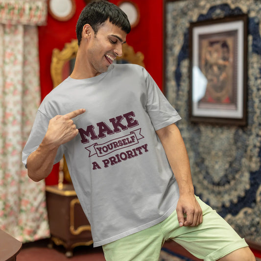 Man wearing a t-shirt with text in a room with decorative walls and furniture.