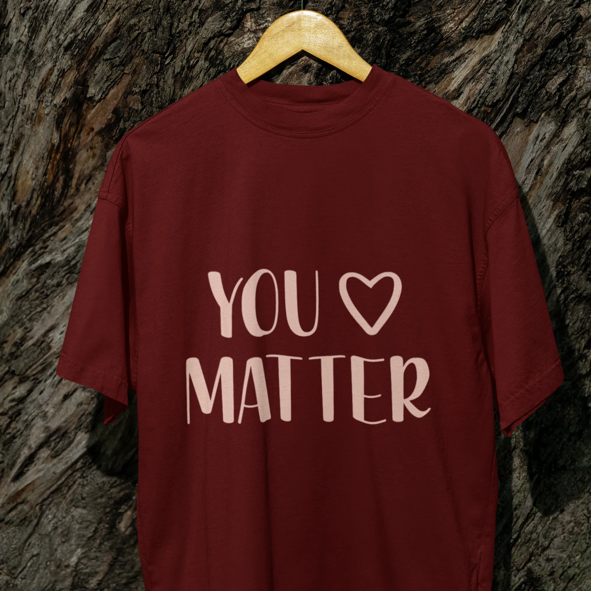 Maroon t-shirt with 'YOU LOVE MATTER' text on a textured wall background