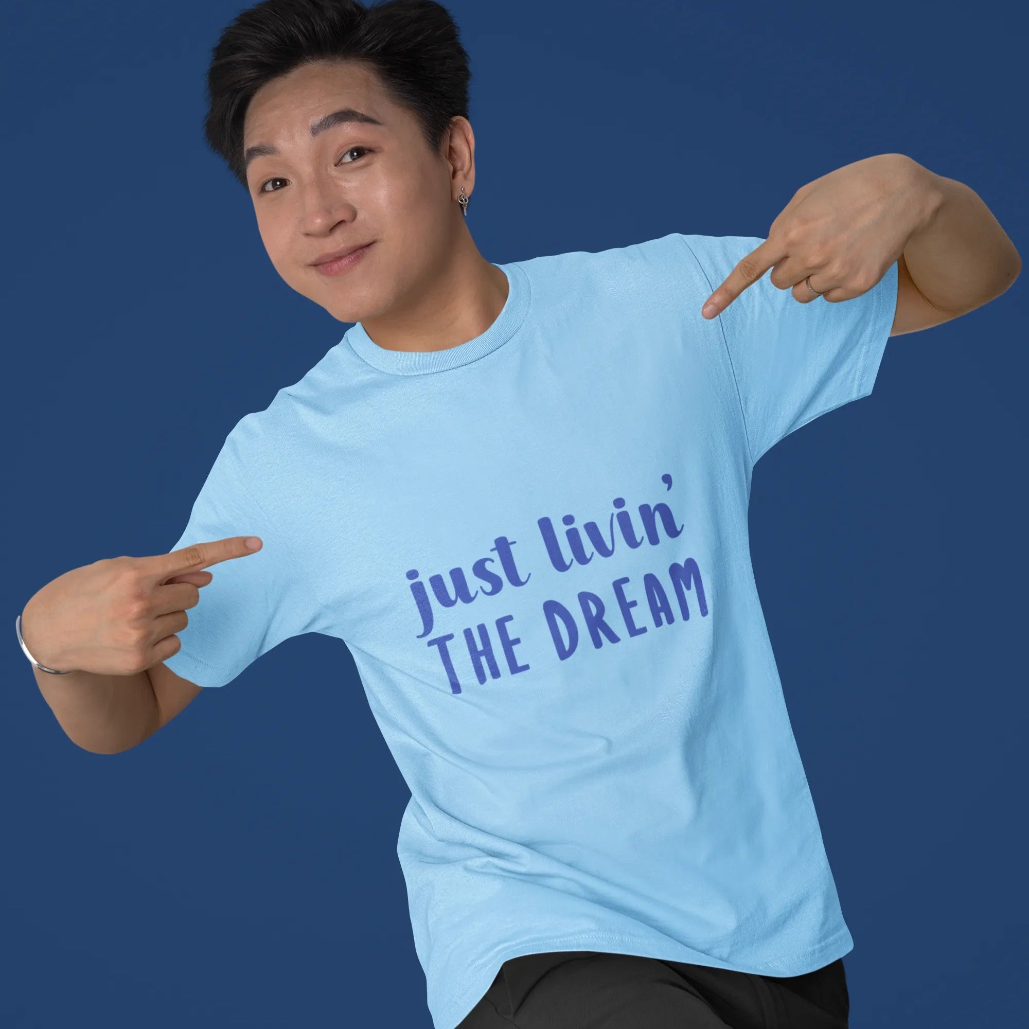 Person wearing a light blue t-shirt with 'just livin' THE DREAM' text on a solid background