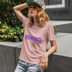 Person wearing a pink t-shirt with 'Be Kind' text, standing outdoors.