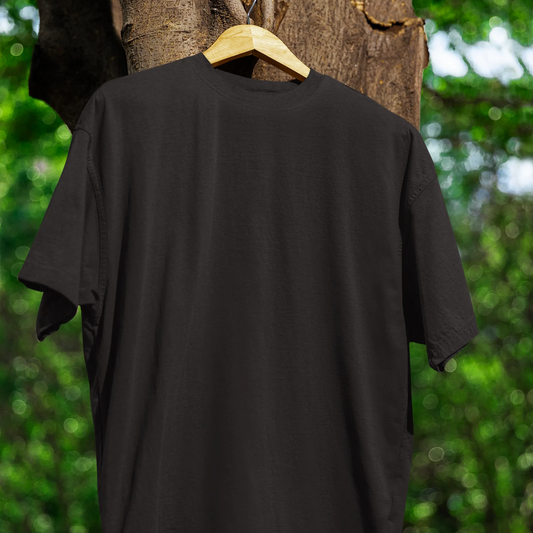 Black t-shirt on a wooden hanger against a natural background