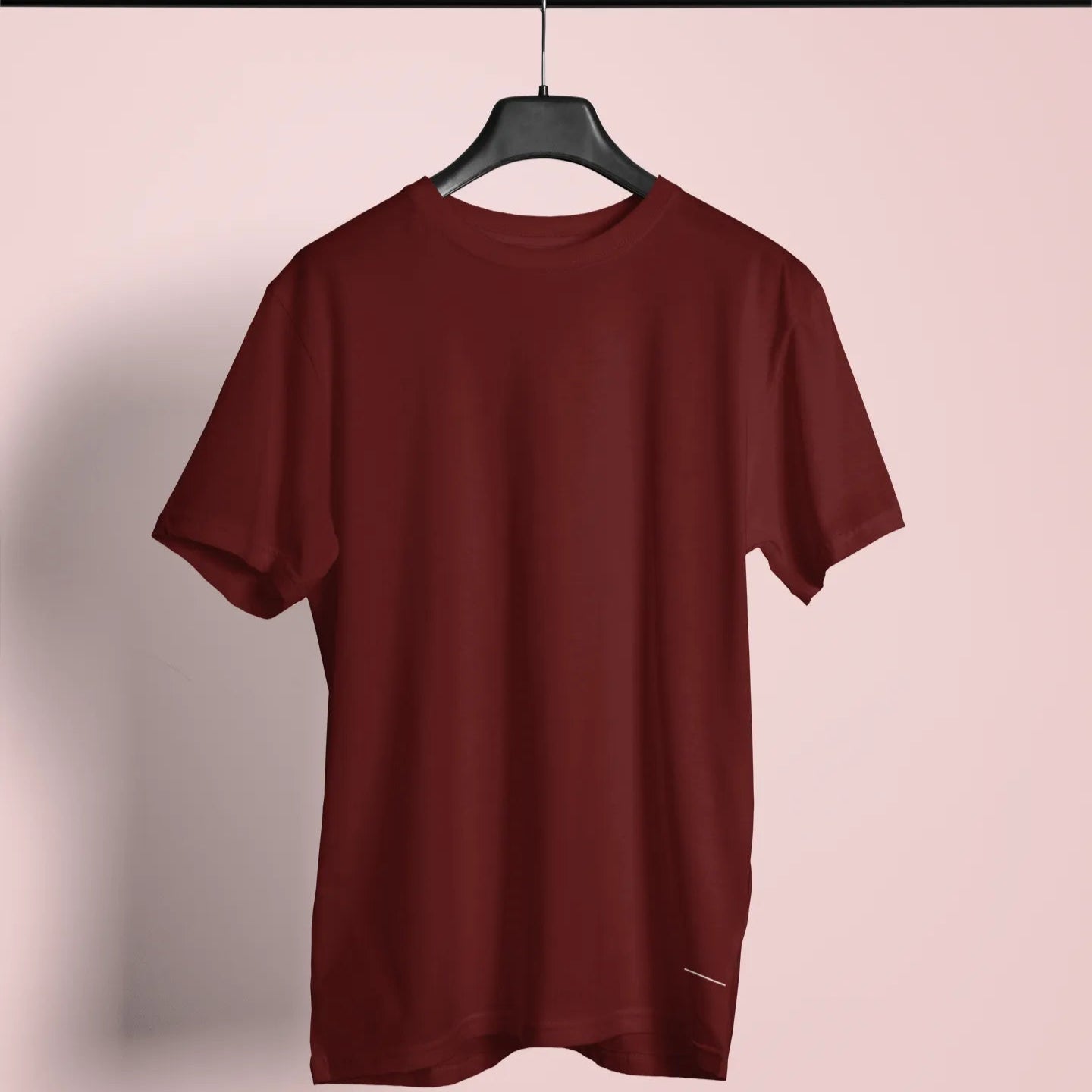 Maroon t-shirt on a hanger against a plain background