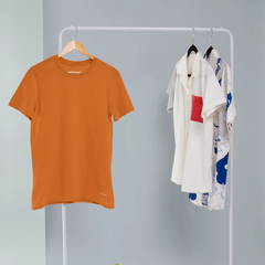 Orange t-shirt and patterned shirts on a white clothing rack against a gray background