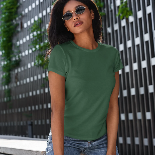 Woman wearing a green t-shirt standing in front of a modern building with greenery.