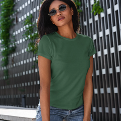 Woman wearing a green t-shirt standing in front of a modern building with greenery.