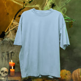 Plain light blue t-shirt on a Halloween-themed background with pumpkins, candles, and cobwebs.