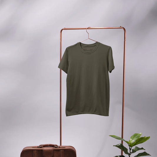 Green t-shirt on a copper rack with a brown suitcase and plant on a gray background