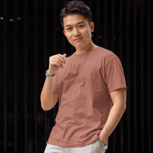 Man wearing a pink t-shirt and white pants against a black background