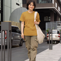 Woman walking on a sidewalk holding a beige bag in an urban setting