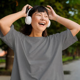 Person wearing headphones and laughing outdoors