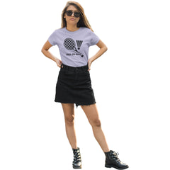 Woman wearing a light purple t-shirt with a graphic design and text, black denim skirt, and black boots on a white background.
