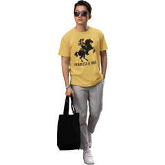 Person wearing a yellow t-shirt with a graphic design and text, holding a black tote bag on a white background