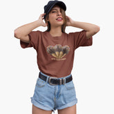 Woman wearing a brown t-shirt with a graphic design and denim shorts on a white background