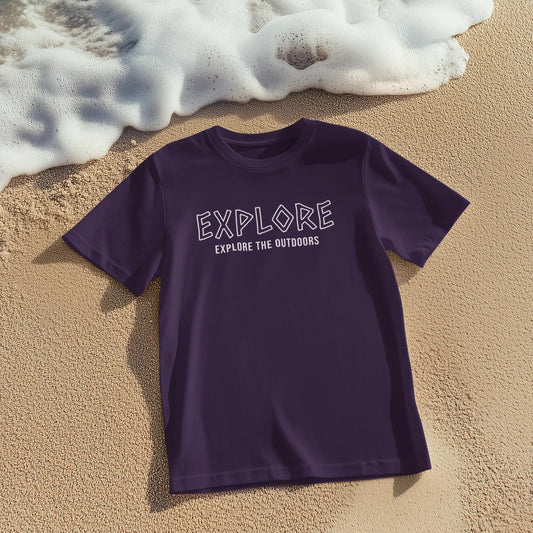 Purple t-shirt with 'EXPLORE EXPLORE THE OUTDOORS' text on sand with ocean waves in background