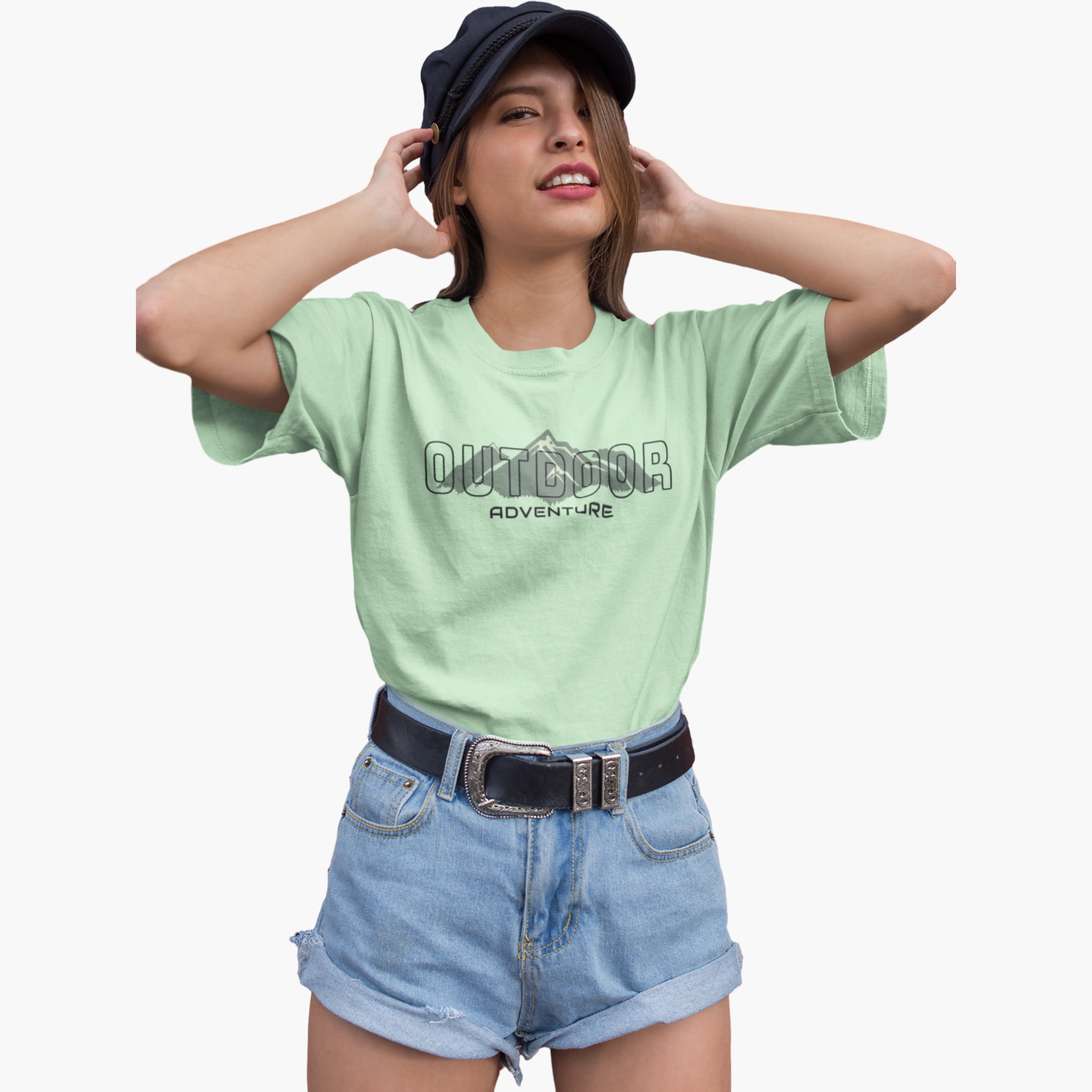 Woman wearing a light green t-shirt with 'Outdoor Adventure' text, blue shorts, and a black cap on a white background