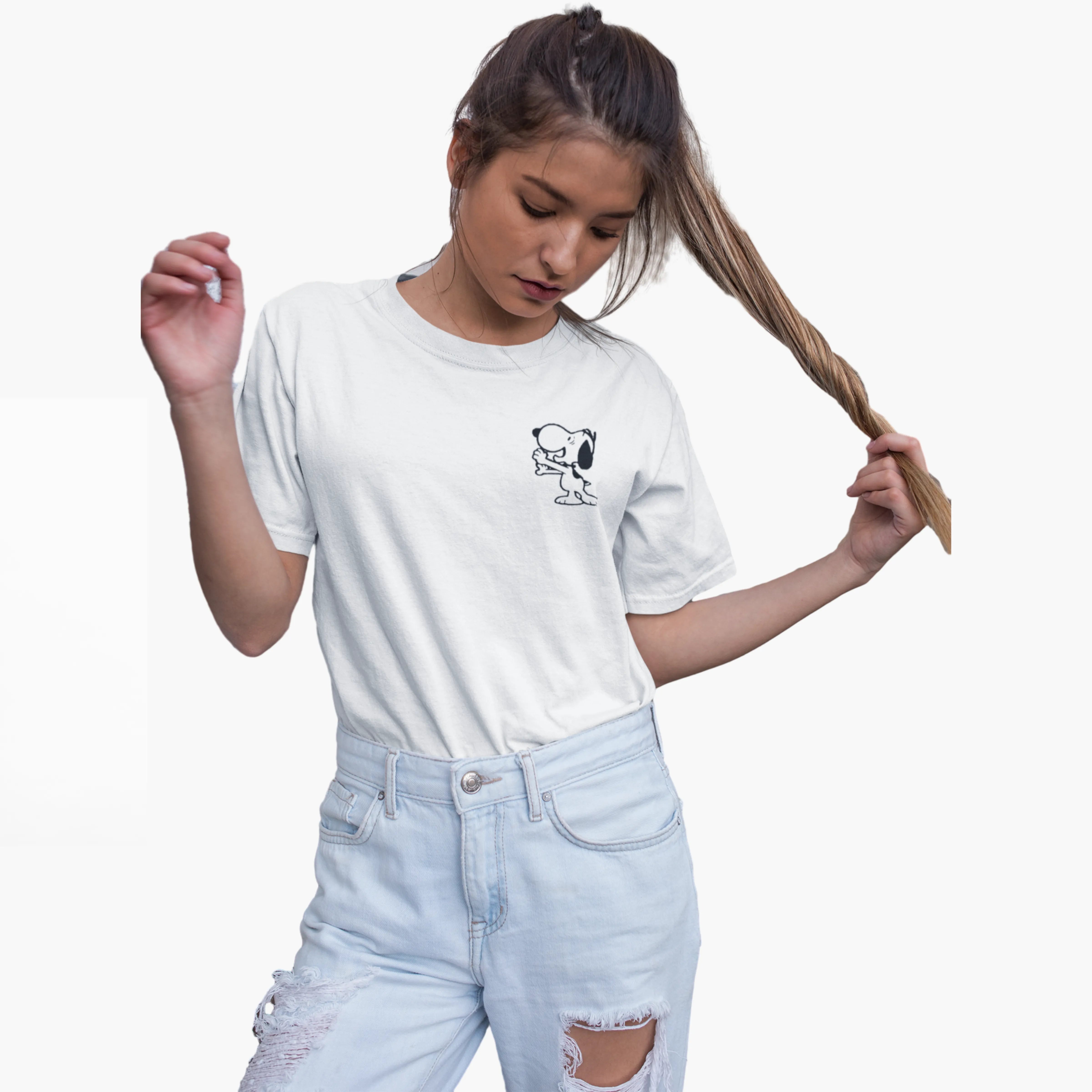 Person wearing a white t-shirt with a graphic design and light blue jeans on a plain background