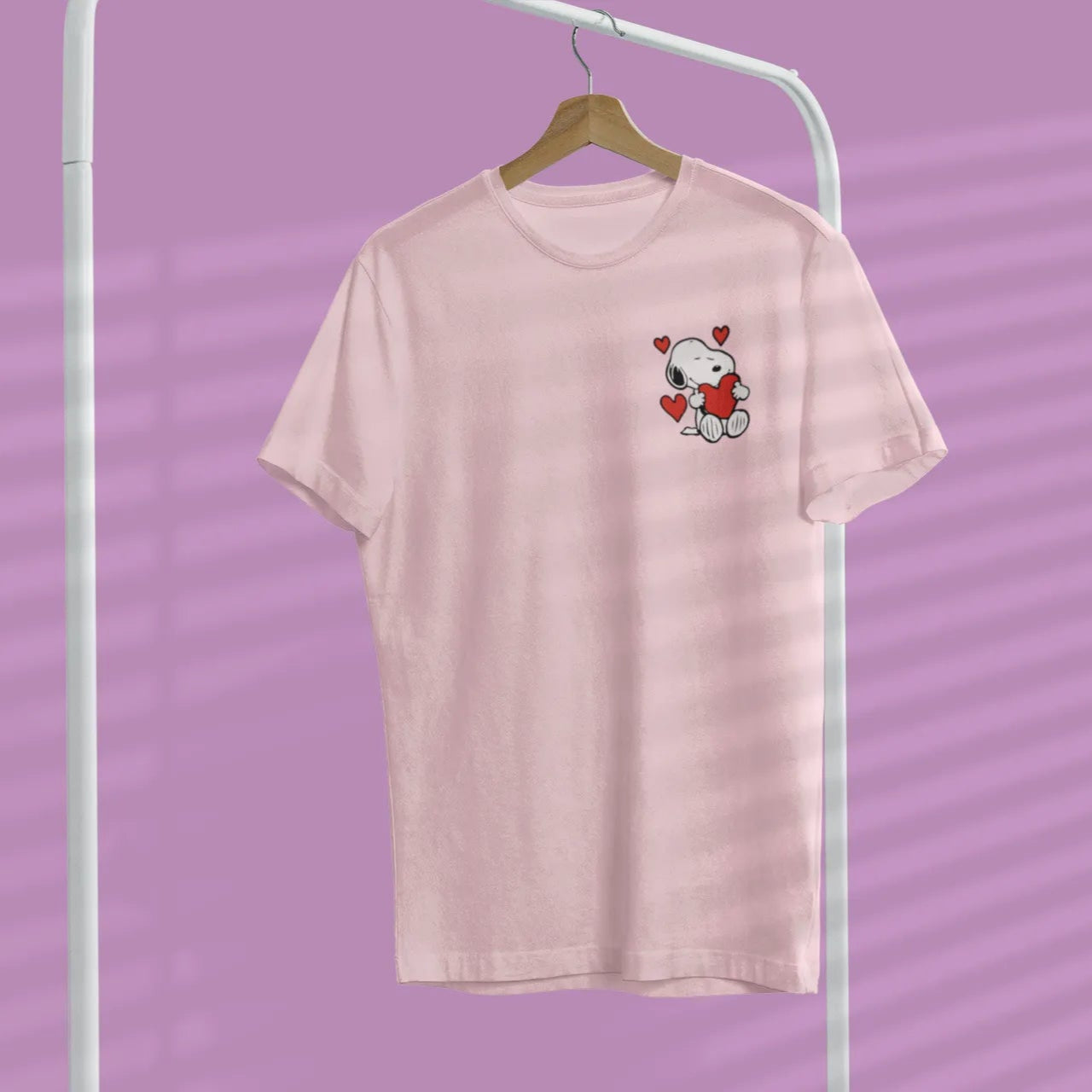 Pink t-shirt with a small graphic on a hanger against a purple background