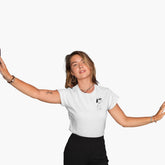 Person wearing a white shirt with a small design on a plain background