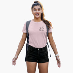 Woman wearing a pink t-shirt with a graphic design and black shorts, standing against a white background.