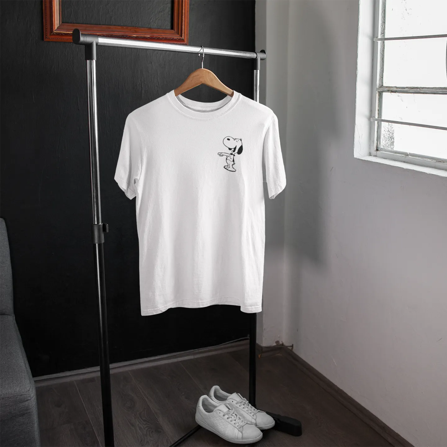 White t-shirt with a small graphic on a hanger in a room with a window.