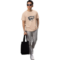 Person wearing a beige t-shirt with a graphic design, holding a black tote bag on a white background