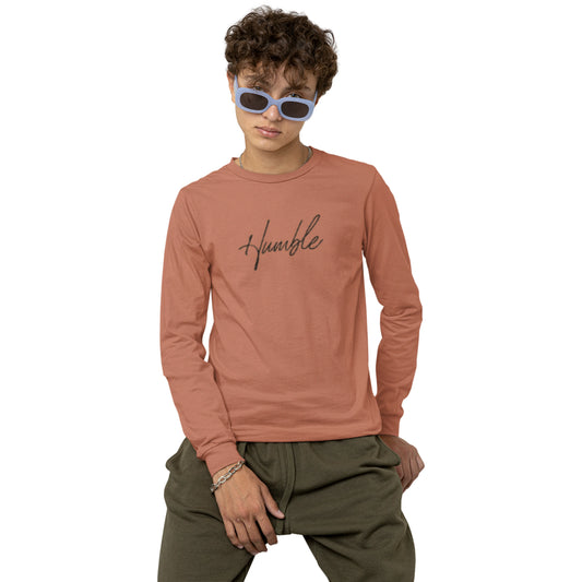 Person wearing a pink long-sleeve shirt with 'humble' text and green pants on a white background