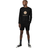 Man wearing a black long-sleeve shirt with a compass design and 'Traveller' text, paired with black shorts on a white background.