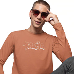 Person wearing a brown long-sleeve shirt with 'Karma' printed on it, posing with sunglasses.