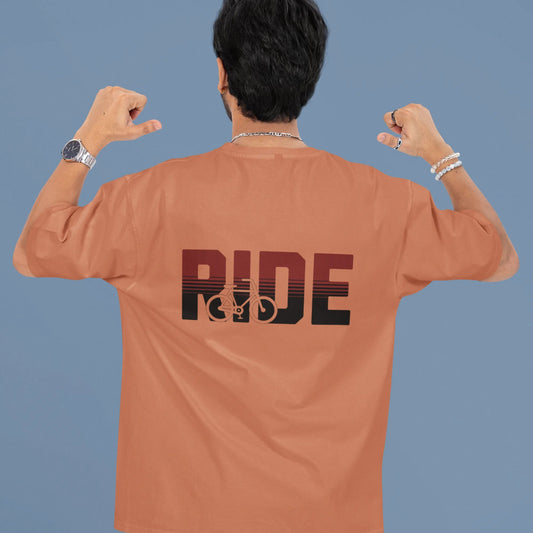 Person wearing a brown t-shirt with 'RIDE' printed on the back against a blue background