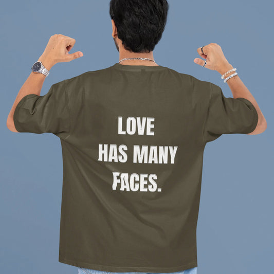Person wearing a green t-shirt with 'LOVE HAS MANY FACES.' text on the back against a blue background
