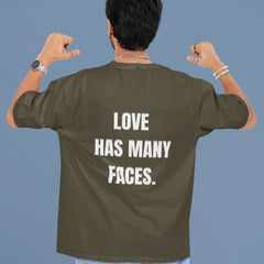 Person wearing a green t-shirt with 'LOVE HAS MANY FACES.' text on the back against a blue background