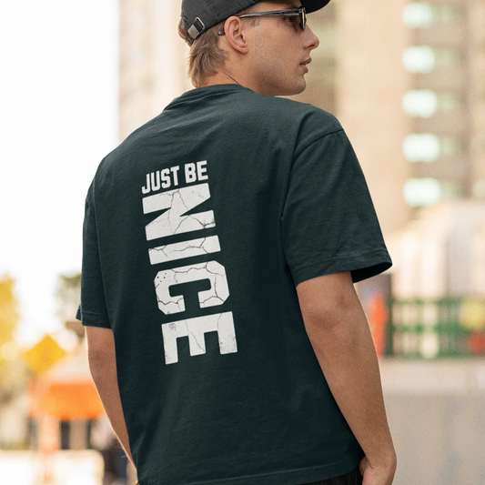 Person wearing a black t-shirt with 'JUST BE NICE' text on the back, standing outdoors.
