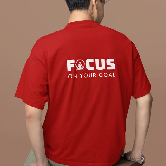 Person wearing a red t-shirt with 'FOCUS ON YOUR GOAL' text on the back against a brown background