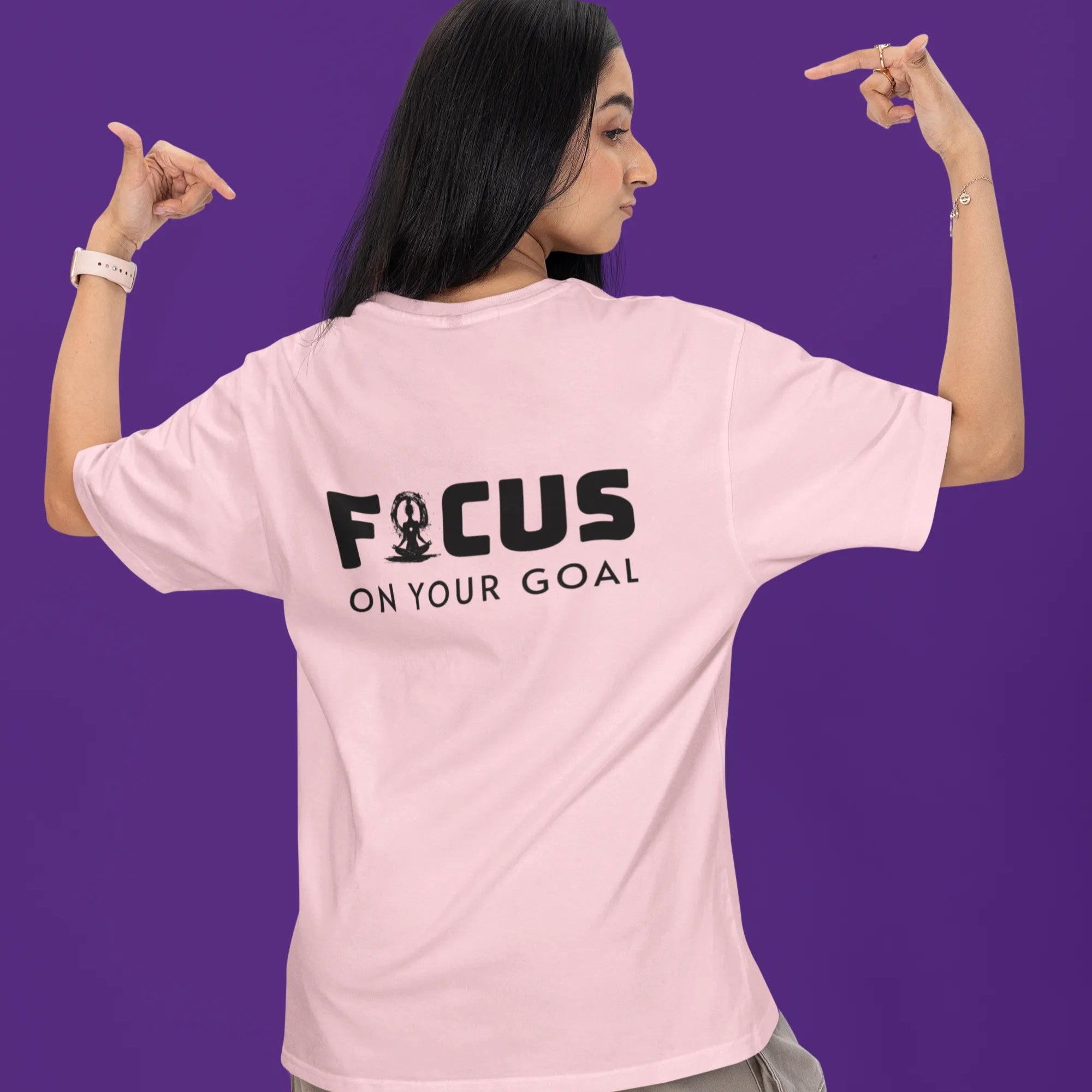 Person wearing a pink t-shirt with 'FOCUS ON YOUR GOAL' text on the back against a purple background