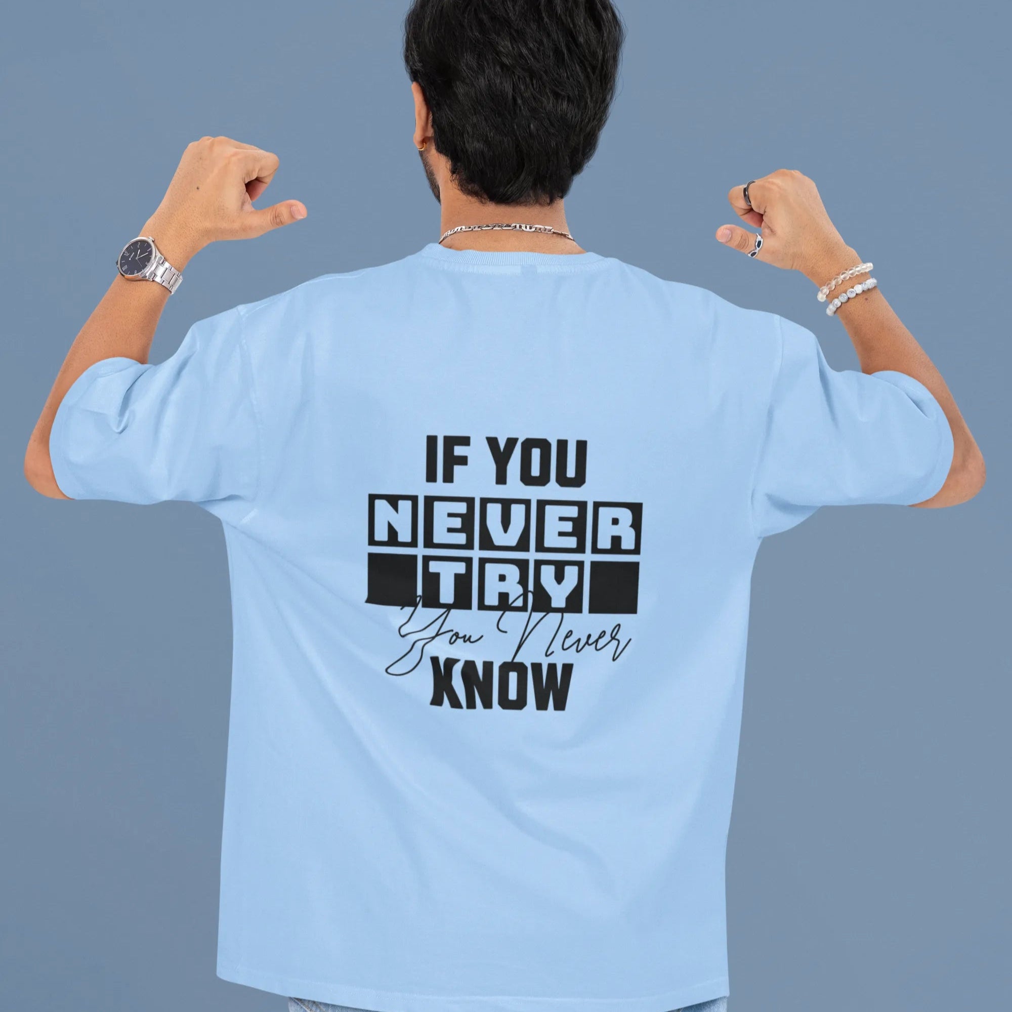Person wearing a light blue t-shirt with motivational text on the back against a gray background