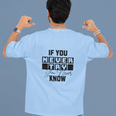 Person wearing a light blue t-shirt with motivational text on the back against a gray background