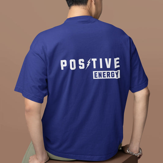 Person wearing a blue t-shirt with 'POSITIVE ENERGY' text on the back against a brown background