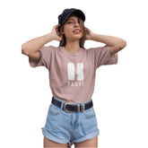 Woman wearing a pink t-shirt with 'PAUSE' design, blue shorts, and a black cap on a white background