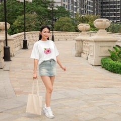 Woman walking on a sidewalk with a scenic background of trees and buildings.