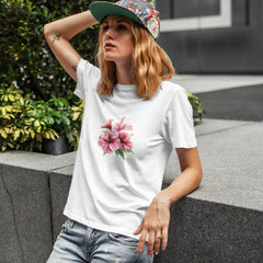 Woman wearing a white t-shirt with a floral design and a colorful cap outdoors.
