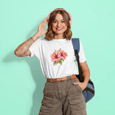 Woman wearing a white t-shirt with a floral design, brown pants, and a blue backpack on a light green background