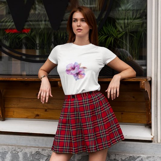 Woman wearing a white t-shirt with a floral design and a red plaid skirt sitting on a wooden bench.