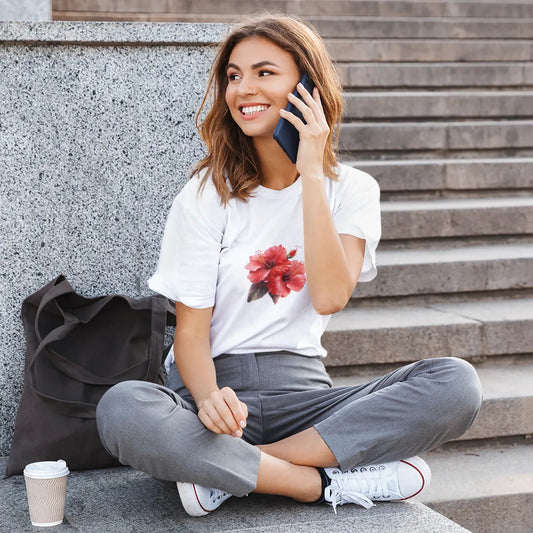 Woman sitting on steps talking on a phone with a coffee cup nearby
