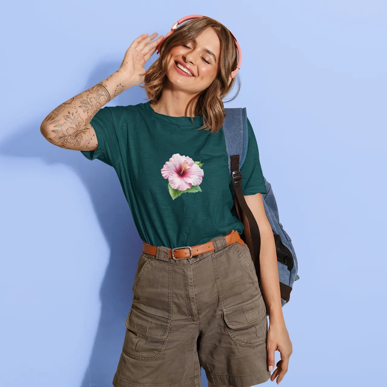 Woman wearing a green t-shirt with a pink flower design against a light blue background